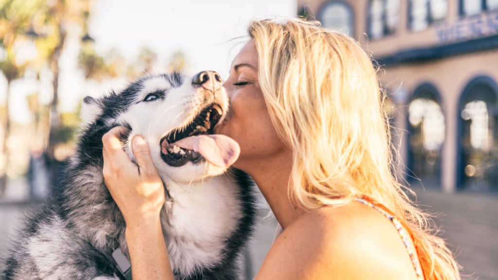 woman kissing dog on cheek